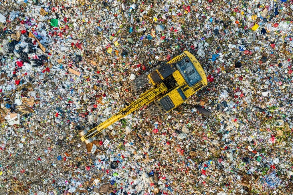 Aerial shot of a landfill with a yellow excavator in South Tangerang, Indonesia.