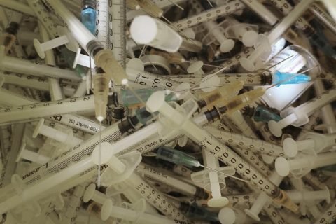 Close-up view of numerous medical syringes and vaccine vials used for immunization.